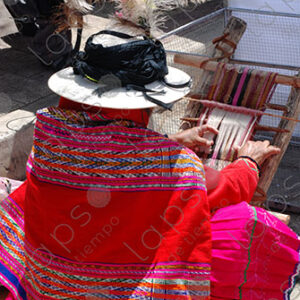 A woman in traditional attire weaving on a loom