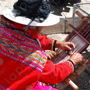 A woman in traditional attire weaving on a loom
