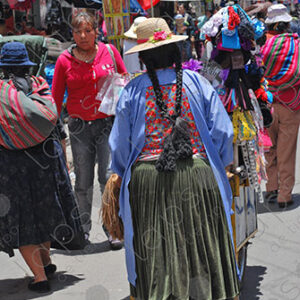 Cholita carries a cart of merchandise