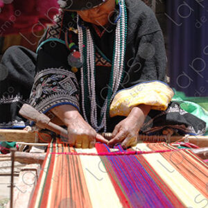 Indigenous woman working on loom smiles