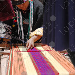 Indigenous woman working on loom smiles