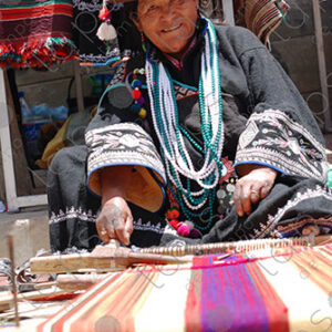 Indigenous woman working on loom smiles