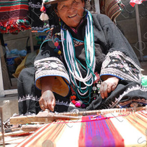 Indigenous woman working on loom smiles