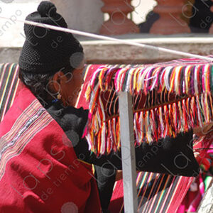 Indigenous woman working on a red loom