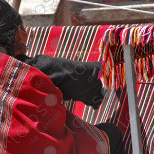 Indigenous woman working on a red loom