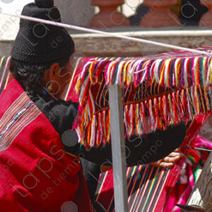 Indigenous woman working on a red loom