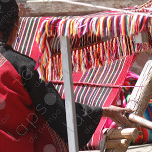 Indigenous woman working on a red loom