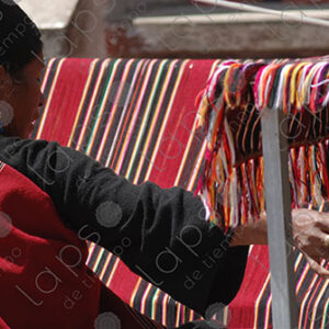 Indigenous woman working on a red loom
