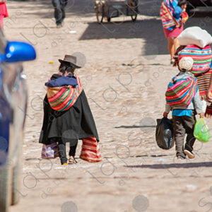 Locals in traditional dress walking and holding bags Tarabuco, Bolivia