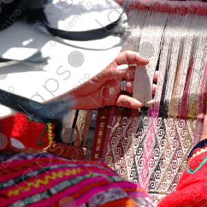 Woman in traditional indigenous attire weaving on a loom
