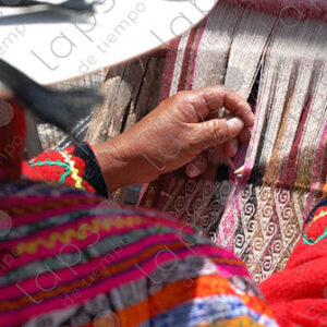 Woman in traditional indigenous attire weaving on a loom