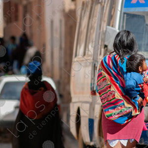 Woman walks carrying a child on her back