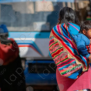 Woman walks carrying a child on her back
