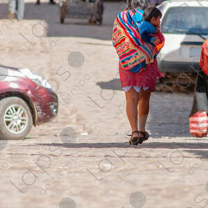 Woman walks carrying a child on her back