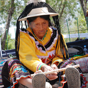 Indigenous old woman weaves with a foot loom