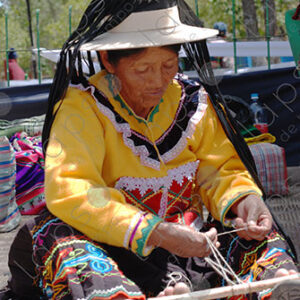 Indigenous old woman weaves with a foot loom