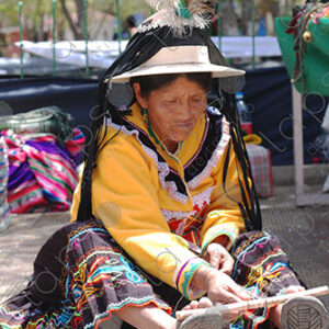Indigenous old woman weaves with a foot loom