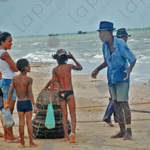 Man with cage baskets and women and children shopping on the seashore