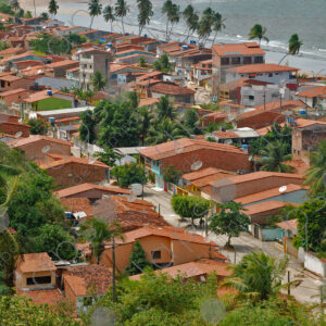 Several houses with tiled roofs and sea in the background