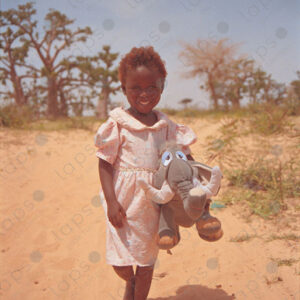 Girl posing with a plush toy amidst baobab fields