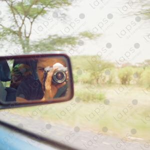 Reflection of the photographer with an old camera in the rearview mirror