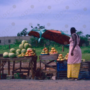 Woman selling fruit seen from a moving car
